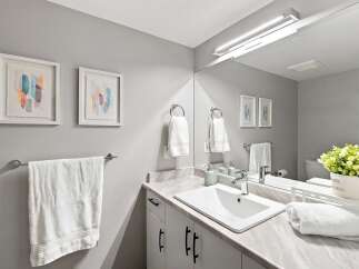 This modern bathroom features a sleek vanity with a marble countertop and a white undermount sink, complemented by minimalist black hardware.