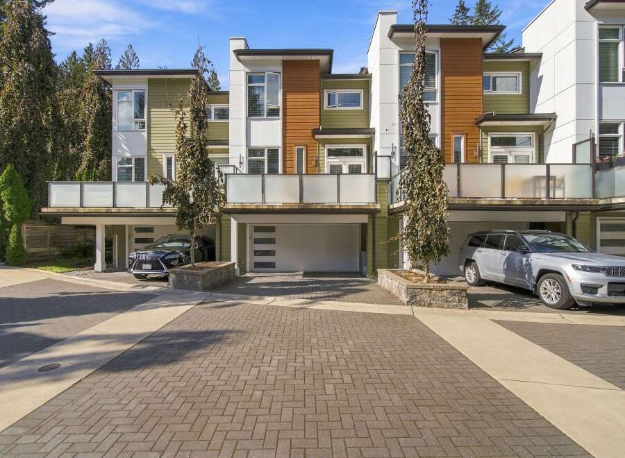 Experience modern living in this stunning townhouse featuring a sleek contemporary design with a mix of green and wood-paneled exteriors.