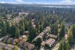 Discover this stunning aerial view of a suburban neighborhood nestled amongst lush evergreen trees, showcasing a harmonious blend of modern townhouses and single-family homes.