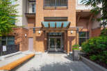 Discover modern living in this brick building featuring a welcoming entrance with a wooden pergola and glass canopy.