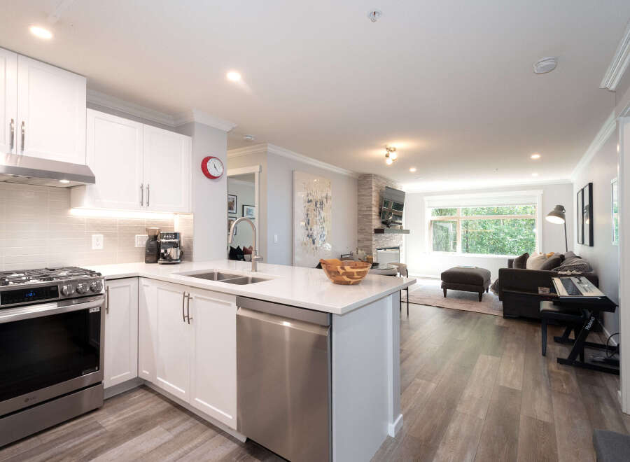 Experience modern living in this beautifully renovated condo featuring a sleek white kitchen with stainless steel appliances and a spacious island perfect for entertaining.