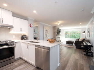Experience modern living in this beautifully renovated condo featuring a sleek white kitchen with stainless steel appliances and a spacious island perfect for entertaining.