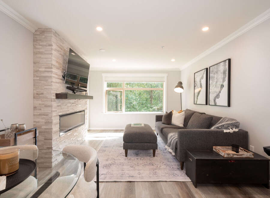 Experience modern living in this beautifully appointed living room, featuring a sleek fireplace with a stacked stone accent wall and a mounted flat-screen TV.