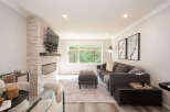 Experience modern living in this beautifully appointed living room, featuring a sleek fireplace with a stacked stone accent wall and a mounted flat-screen TV.