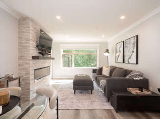 Experience modern living in this beautifully appointed living room, featuring a sleek fireplace with a stacked stone accent wall and a mounted flat-screen TV.