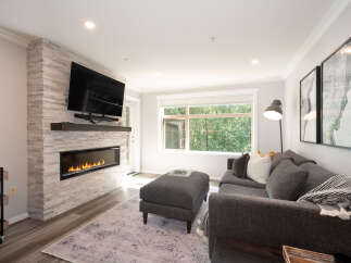 Experience modern living in this stylish living room, featuring a sleek gas fireplace set against a textured stone accent wall.