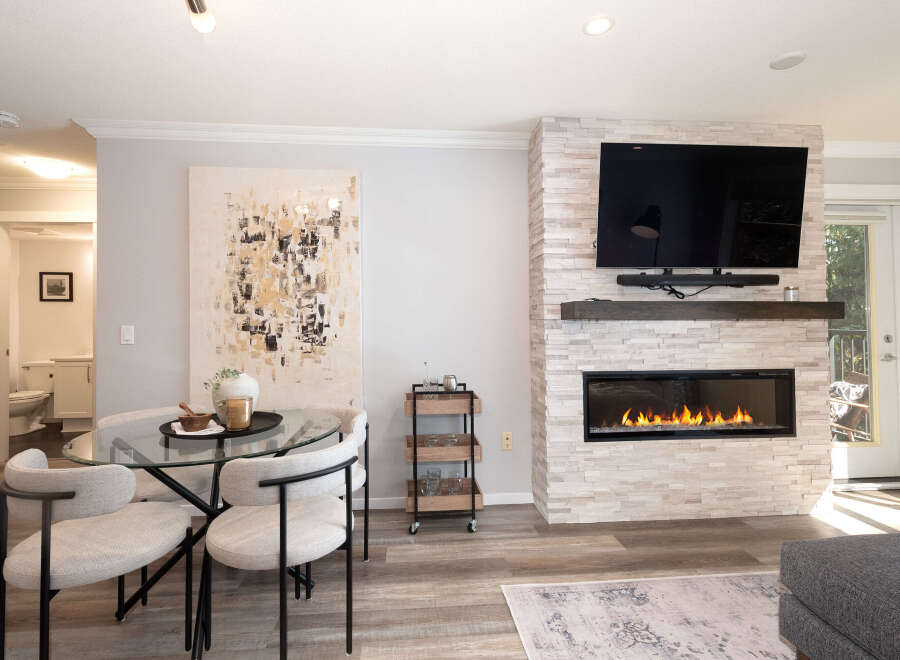 Experience modern living in this beautifully appointed space, featuring a sleek gas fireplace with a stacked stone surround and a large flat-screen TV.