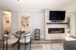 Experience modern living in this beautifully appointed space, featuring a sleek gas fireplace with a stacked stone surround and a large flat-screen TV.