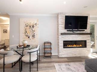 Experience modern living in this beautifully appointed space, featuring a sleek gas fireplace with a stacked stone surround and a large flat-screen TV.