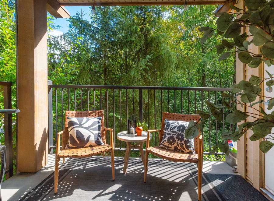 Enjoy your morning coffee or evening relaxation on this charming covered balcony, offering a serene retreat amidst lush greenery.
