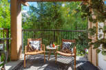 Enjoy your morning coffee or evening relaxation on this charming covered balcony, offering a serene retreat amidst lush greenery.