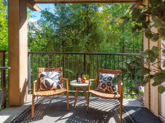 Enjoy your morning coffee or evening relaxation on this charming covered balcony, offering a serene retreat amidst lush greenery.