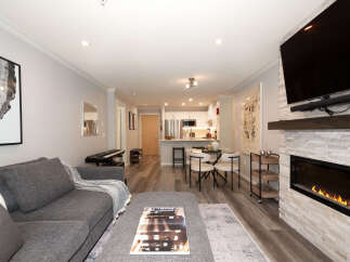 Experience modern living in this open-concept space featuring a sleek kitchen with stainless steel appliances and a dining area perfect for intimate meals.