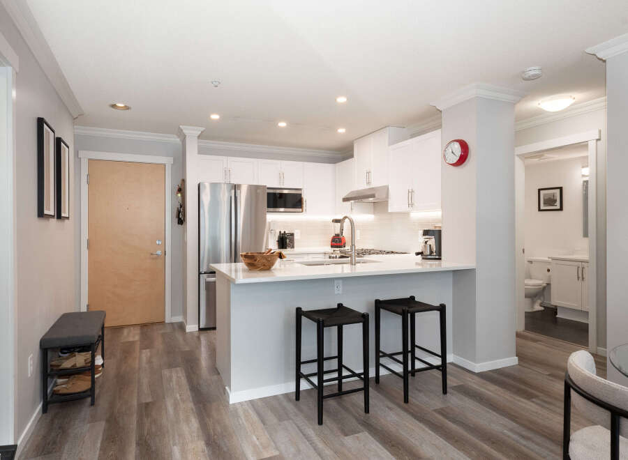 Discover modern living in this stylish condo featuring a sleek kitchen with stainless steel appliances and a convenient breakfast bar.