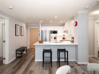 Discover modern living in this beautifully appointed condo featuring a sleek, white kitchen with stainless steel appliances and a spacious island perfect for casual dining.