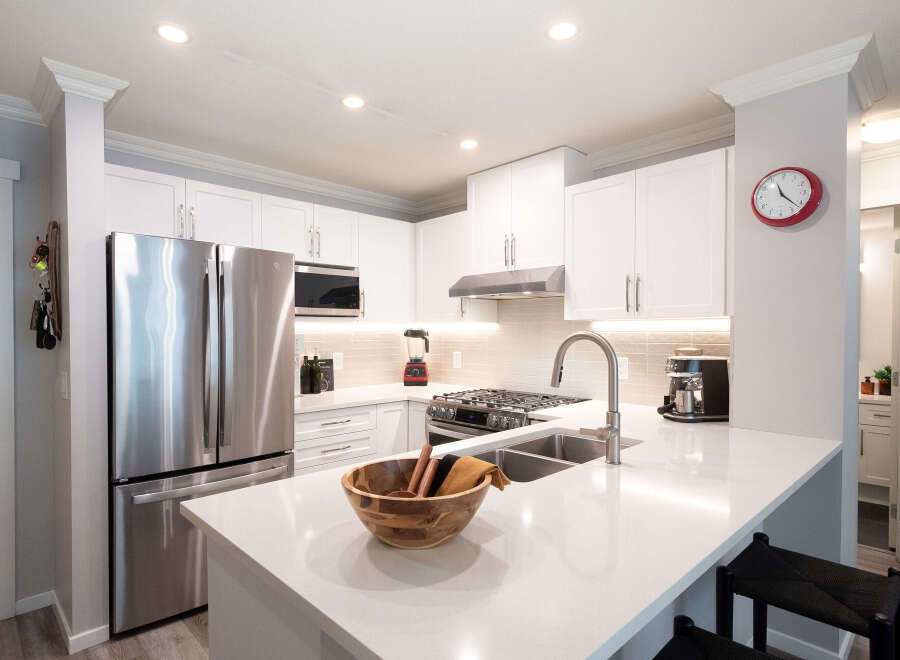 Discover this modern kitchen featuring sleek white cabinetry and a spacious quartz countertop island, perfect for meal prep and casual dining.