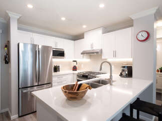 Discover this modern kitchen featuring sleek white cabinetry and a spacious quartz countertop island, perfect for meal prep and casual dining.