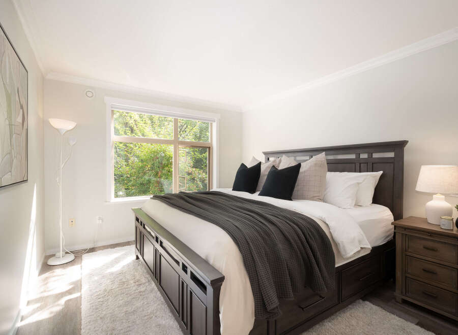 Experience tranquility in this inviting bedroom, featuring a spacious king-sized bed adorned with plush pillows and a cozy dark gray throw.