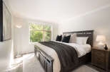 Experience tranquility in this inviting bedroom, featuring a spacious king-sized bed adorned with plush pillows and a cozy dark gray throw.