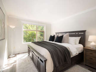 Experience tranquility in this inviting bedroom, featuring a spacious king-sized bed adorned with plush pillows and a cozy dark gray throw.
