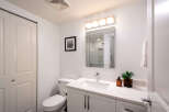 This modern bathroom features a sleek vanity with a white countertop and undermount sink, complemented by a large, beveled mirror and a stylish four-light vanity fixture.