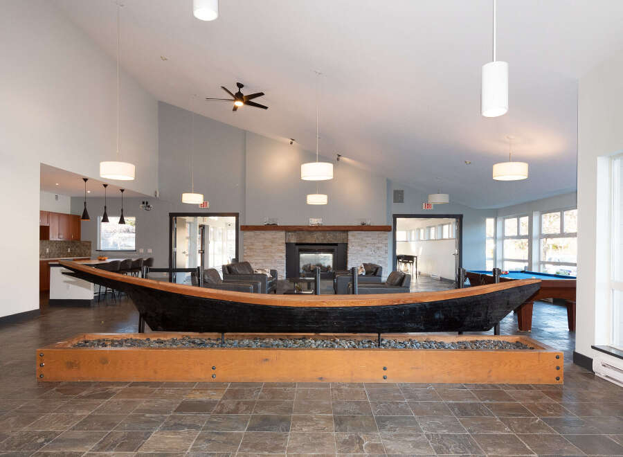 Experience unique living in this spacious common area, featuring a striking canoe centerpiece and a cozy fireplace.