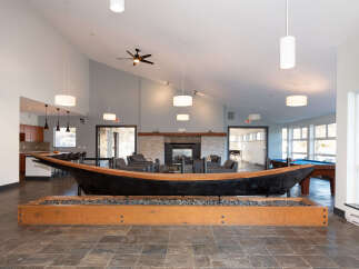 Experience unique living in this spacious common area, featuring a striking canoe centerpiece and a cozy fireplace.