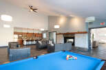 Experience ultimate relaxation and entertainment in this spacious common area, featuring a modern kitchen, a cozy fireplace, and a vibrant pool table.
