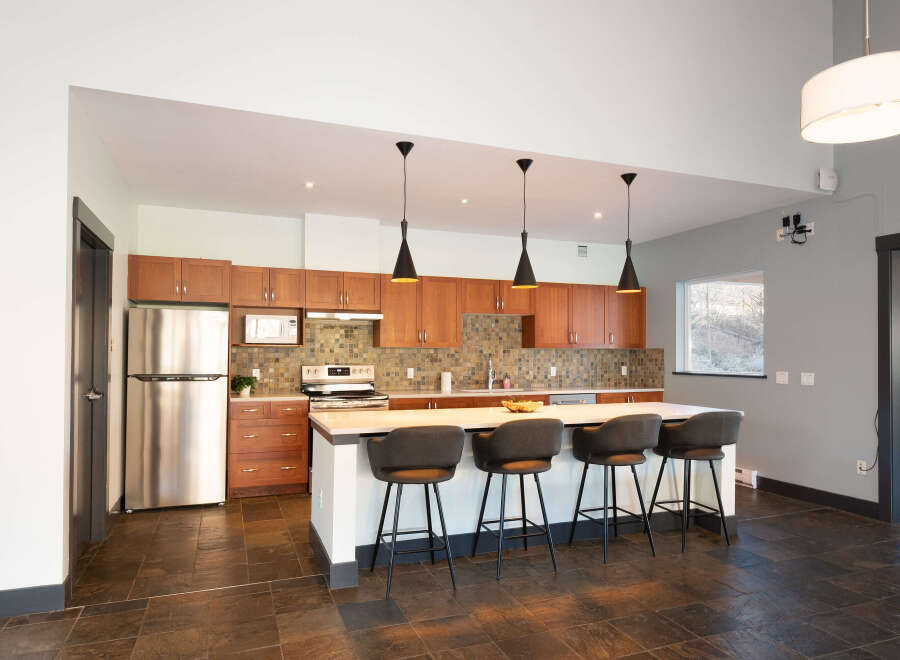 This modern kitchen boasts sleek wooden cabinetry and a spacious island with comfortable bar seating, perfect for casual dining or entertaining.