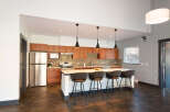 This modern kitchen boasts sleek wooden cabinetry and a spacious island with comfortable bar seating, perfect for casual dining or entertaining.