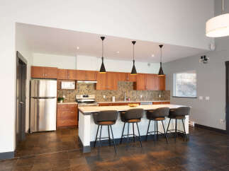 This modern kitchen boasts sleek wooden cabinetry and a spacious island with comfortable bar seating, perfect for casual dining or entertaining.