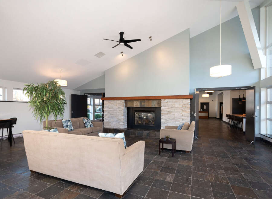 Experience modern living in this spacious lounge area featuring a striking stone fireplace and comfortable seating.