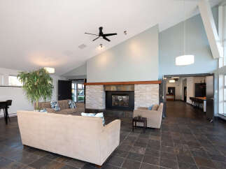 Experience modern living in this spacious lounge area featuring a striking stone fireplace and comfortable seating.