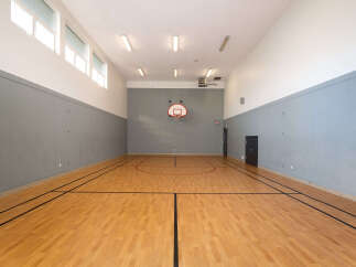 Step onto the polished hardwood court of this indoor gymnasium, perfect for basketball or other recreational activities.