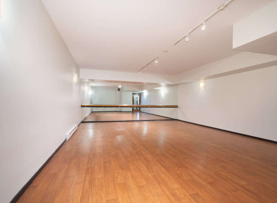 This spacious dance studio features a polished wooden floor, perfect for all types of movement.