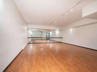 This spacious dance studio features a polished wooden floor, perfect for all types of movement.