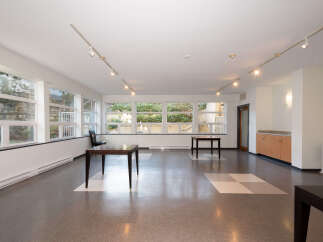 This spacious room features large windows offering abundant natural light and views of the outdoors.