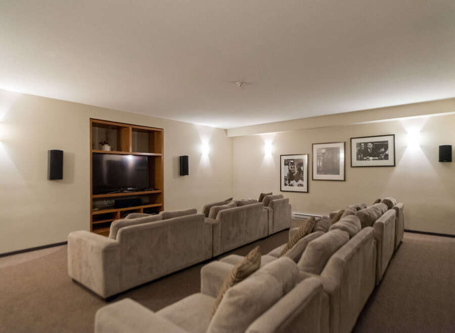 Experience cinematic bliss in this dedicated home theater, featuring plush tiered seating arranged for optimal viewing.