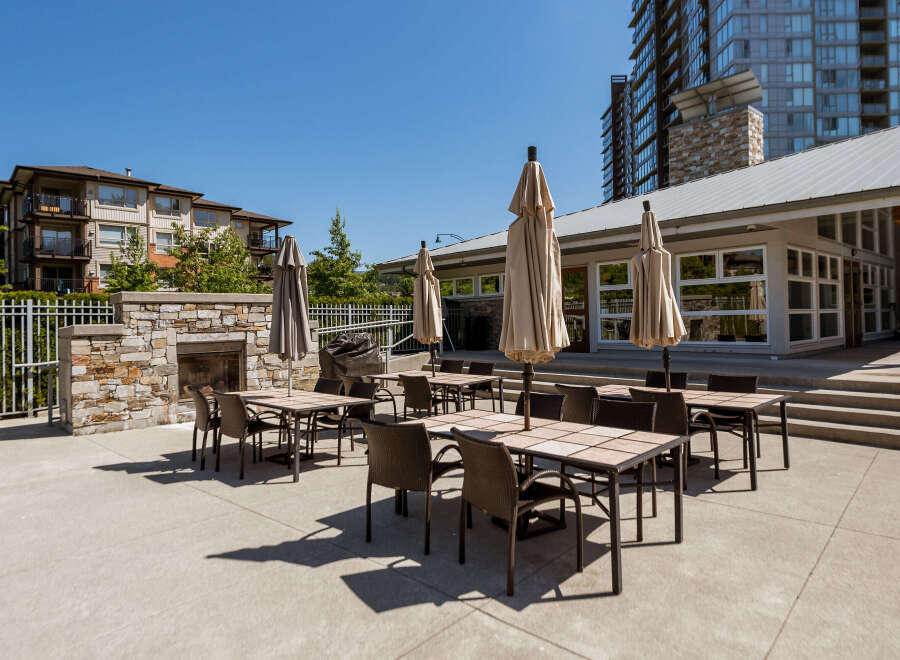 Enjoy outdoor living with this spacious patio area, featuring multiple dining sets and umbrellas perfect for al fresco meals.