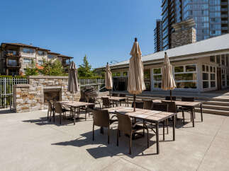 Enjoy outdoor living with this spacious patio area, featuring multiple dining sets and umbrellas perfect for al fresco meals.