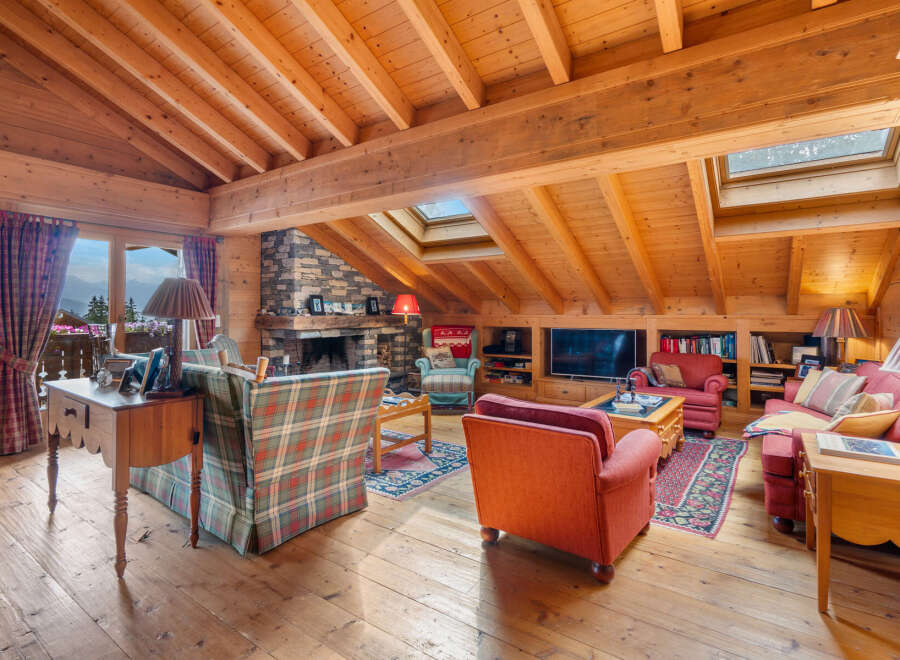 Experience rustic charm in this cozy mountain living room, featuring a grand stone fireplace and exposed wooden beams.