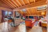Experience rustic charm in this cozy mountain living room, featuring a grand stone fireplace and exposed wooden beams.