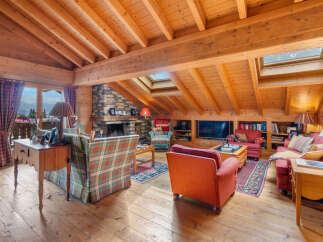 Experience rustic charm in this cozy mountain living room, featuring a grand stone fireplace and exposed wooden beams.