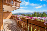 Experience breathtaking mountain views from this charming wooden balcony, adorned with vibrant flower boxes.