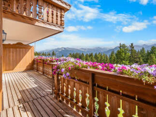 Experience breathtaking mountain views from this charming wooden balcony, adorned with vibrant flower boxes.
