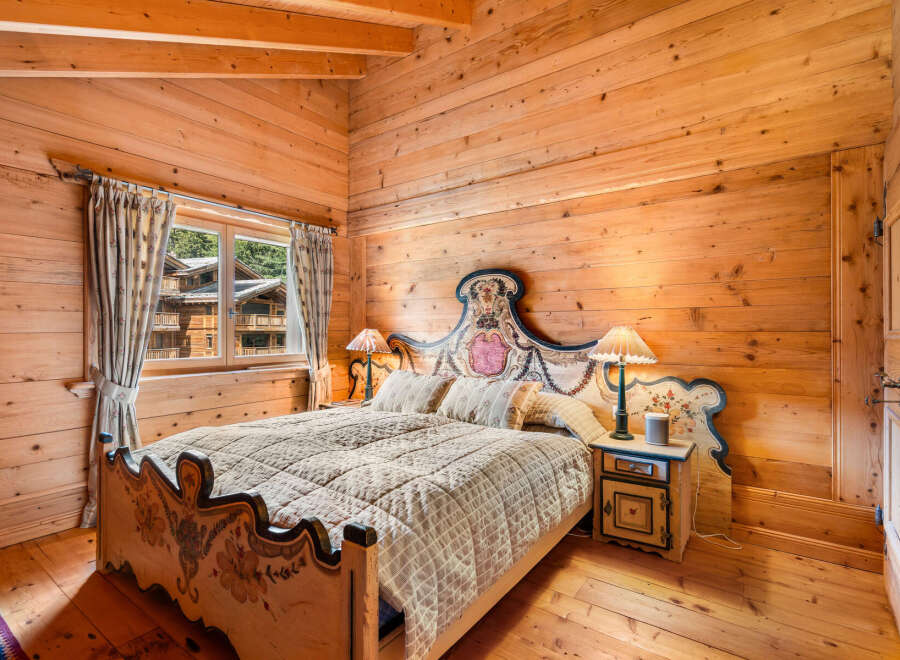 Experience rustic charm in this beautifully appointed wooden bedroom, featuring a queen-sized bed with a decorative headboard and matching footboard.