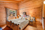 Experience rustic charm in this beautifully appointed wooden bedroom, featuring a queen-sized bed with a decorative headboard and matching footboard.