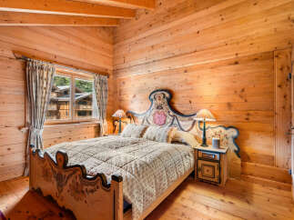 Experience rustic charm in this beautifully appointed wooden bedroom, featuring a queen-sized bed with a decorative headboard and matching footboard.