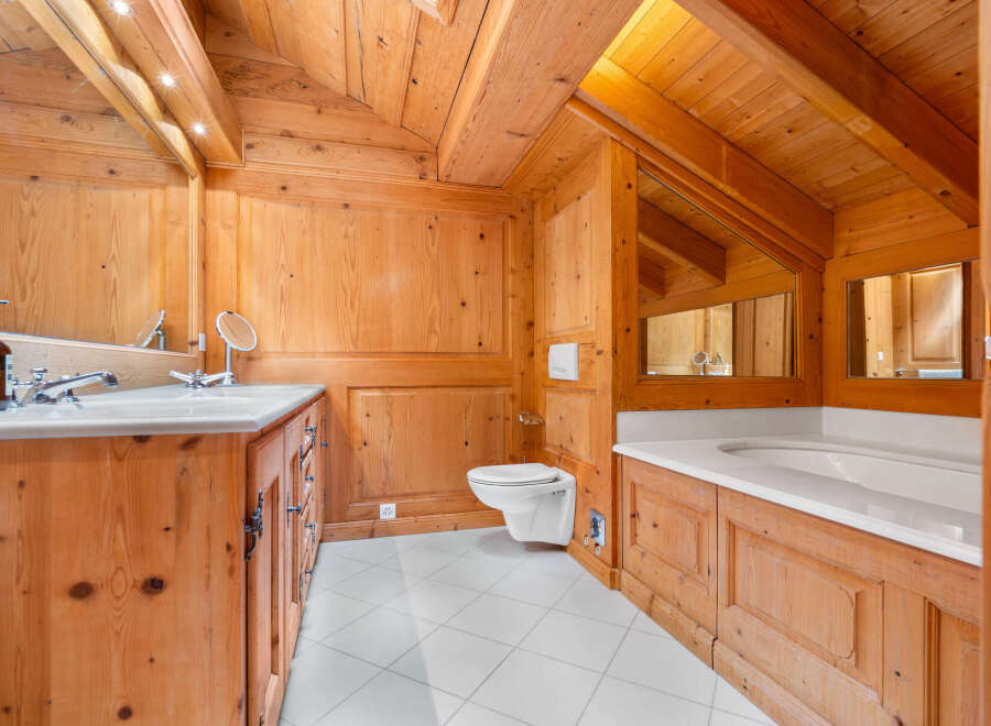 Experience rustic luxury in this charming bathroom, featuring warm wooden paneling throughout and a spacious bathtub perfect for relaxation.