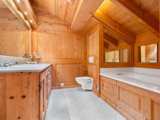 Experience rustic luxury in this charming bathroom, featuring warm wooden paneling throughout and a spacious bathtub perfect for relaxation.